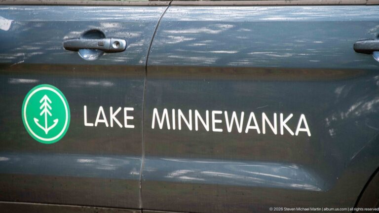 Lake Minnewanka name and green tree emblem painted on a dark vehicle door.