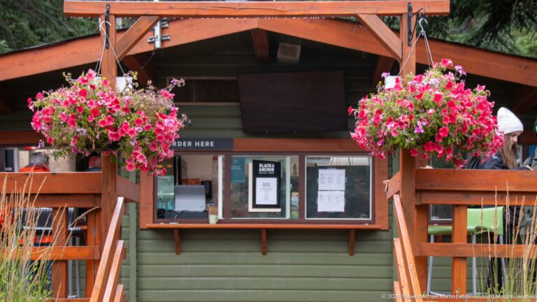Rustic Lake Minnewanka service kiosk framed by two large hanging flower baskets.
