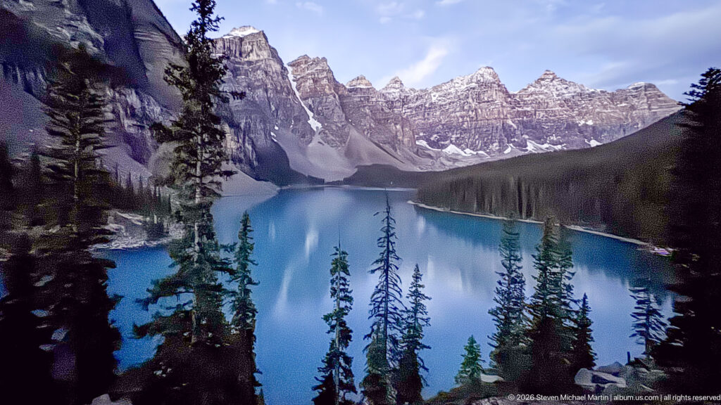 Conifers frame blue Moraine Lake and the jagged, snow-flecked mountains of the Valley of the Ten Peaks.