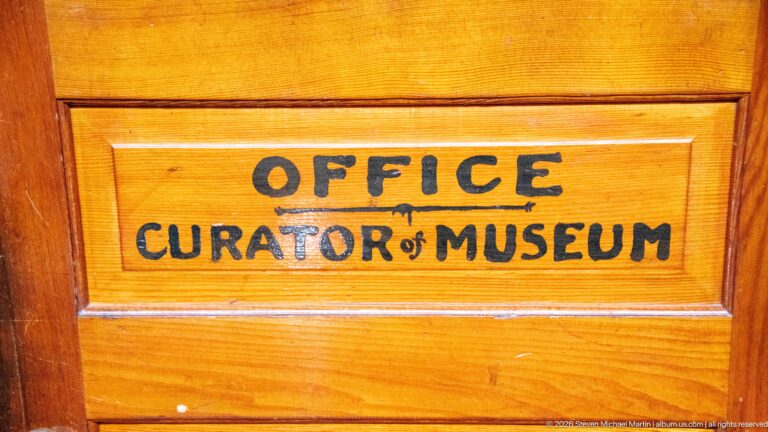 Wooden door panel painted with the words “OFFICE CURATOR of MUSEUM.”
