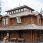 Corner view of the timber Banff Park Museum with shingled roof, veranda, diagonal bracing, and clerestory.