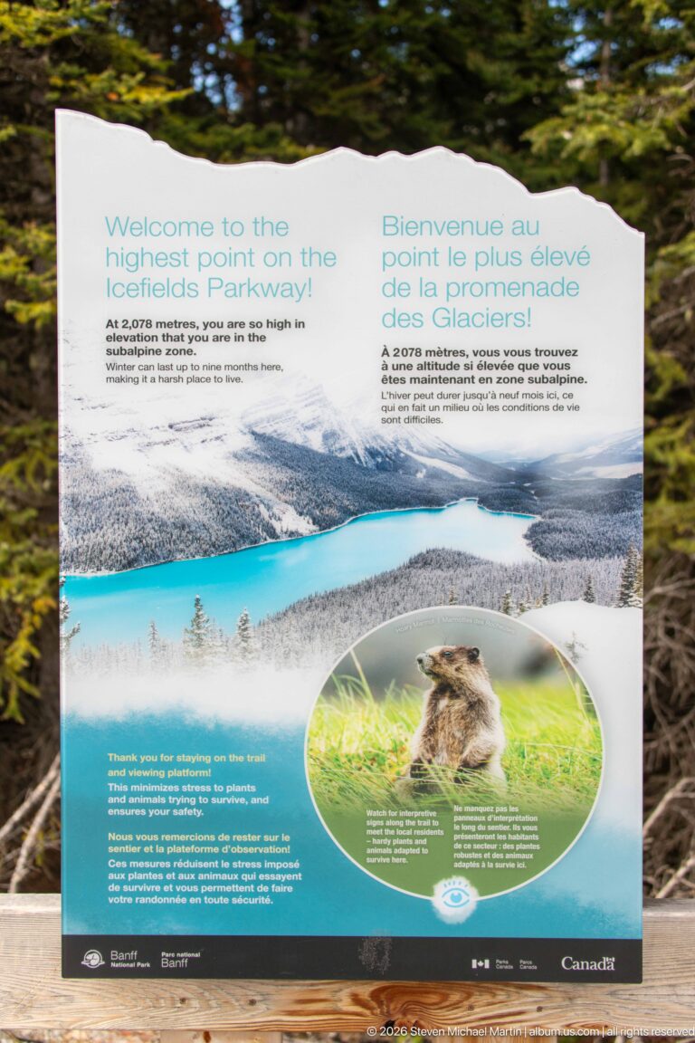 Bilingual Parks Canada panel welcoming visitors to the highest point on the Icefields Parkway, with mountain and turquoise-lake imagery.
