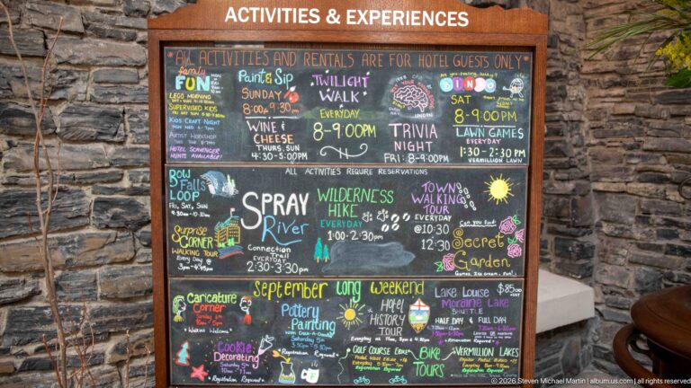 Colorful hand-lettered hotel activities board lists walks, games, tours, hikes, food events, and other guest experiences.