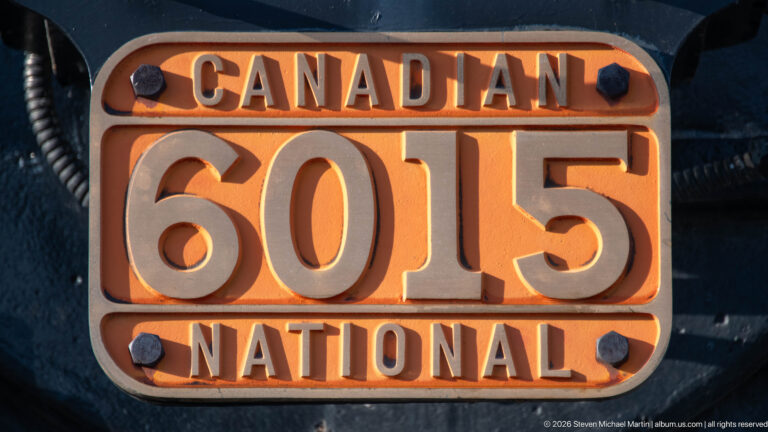 Orange and cream cast plate reading “Canadian 6015 National” mounted on the black locomotive body.