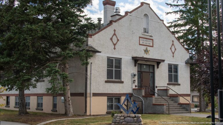 White stucco Cascade Lodge No. 5 building with shaped gable, front steps, and Masonic symbols.