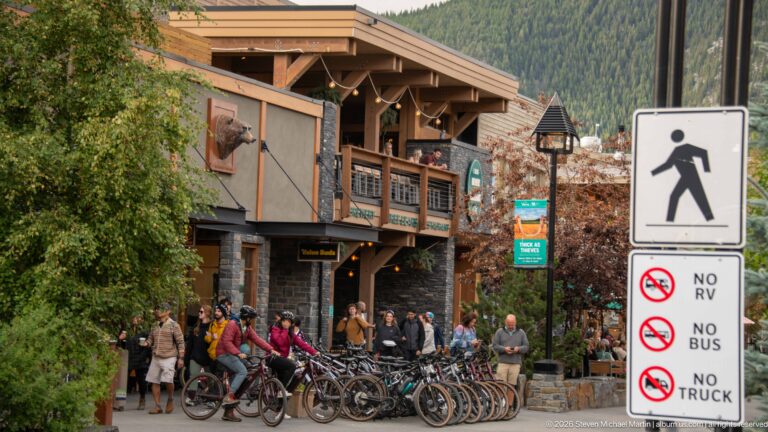 Row of rental bicycles outside a timber building beside pedestrian and vehicle-restriction signs.