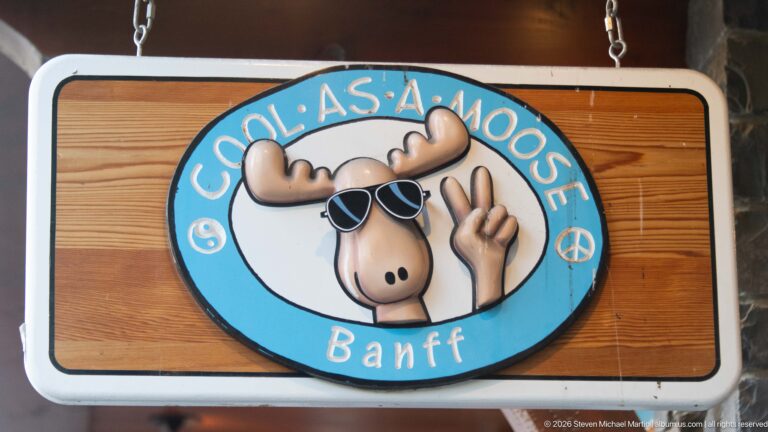Oval “Cool As A Moose Banff” sign with cartoon moose wearing sunglasses and making a peace sign.