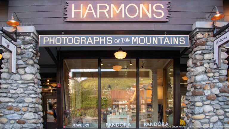 Harmons storefront framed by fieldstone columns with “Photographs of the Mountains” sign above the entrance.