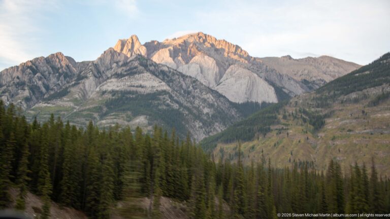 Pale jagged limestone ridge above dark conifer forest and exposed lower slopes in the Bow Valley.