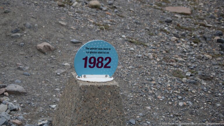 A blue marker mounted on a concrete post states that the glacier was at this location in 1982.