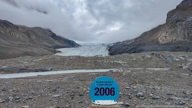 Blue 2006 Athabasca Glacier position marker on rocky forefield with the present glacier in the distance.