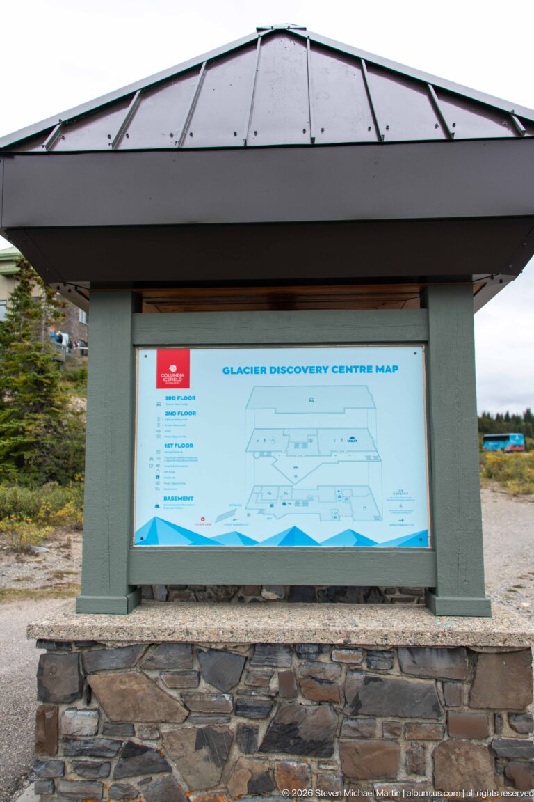 Outdoor kiosk displaying a Glacier Discovery Centre map beneath a broad metal roof.
