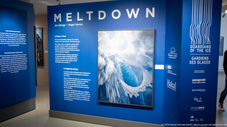 Blue MELTDOWN exhibition wall with bilingual text, large aerial glacier photograph, and Guardians of the Ice branding.