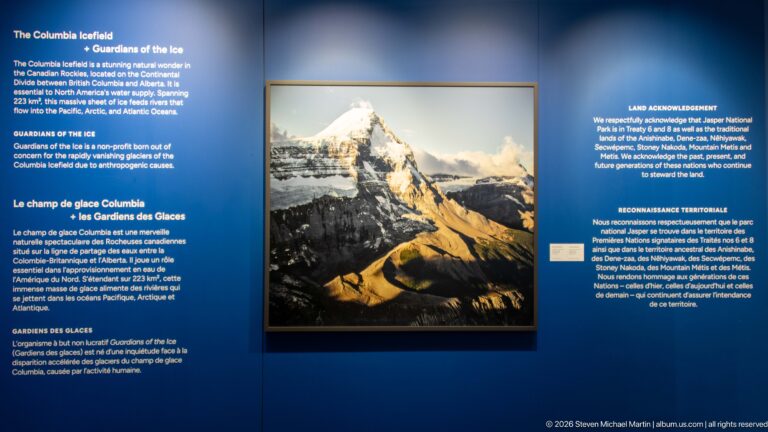 Framed mountain photograph on blue Guardians of the Ice exhibit wall with bilingual interpretive and land-acknowledgement text.