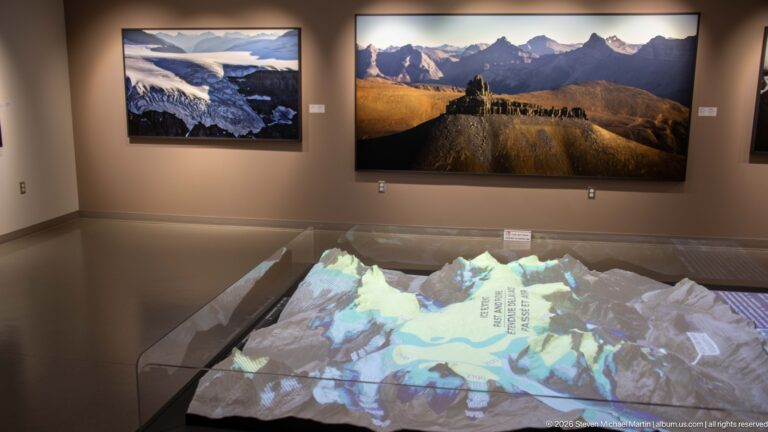 Projected map on a three-dimensional Columbia Icefield relief model beneath large framed mountain photographs.