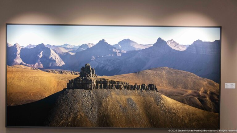 Large framed photograph of a flat-topped eroded ridge in warm light with jagged mountains behind.