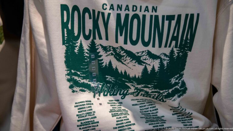 Cream souvenir shirt with green Canadian Rocky Mountain graphic, Hiking Trails lettering, and a list of destinations.
