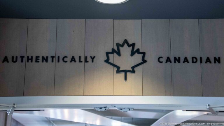 Pale wood wall with black Authentically Canadian lettering and a central maple-leaf outline.