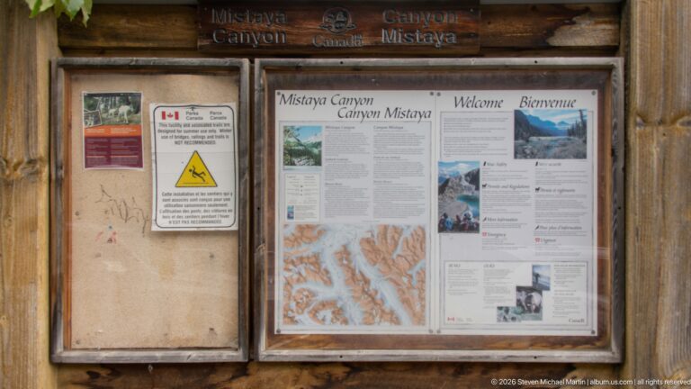 Wooden Mistaya Canyon information kiosk with bilingual Parks Canada maps, photographs, safety notices, and interpretive panels.