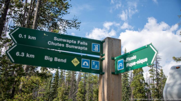 Green Parks Canada trail sign pointing 0.1 km to Sunwapta Falls and 6.3 km toward Big Bend.