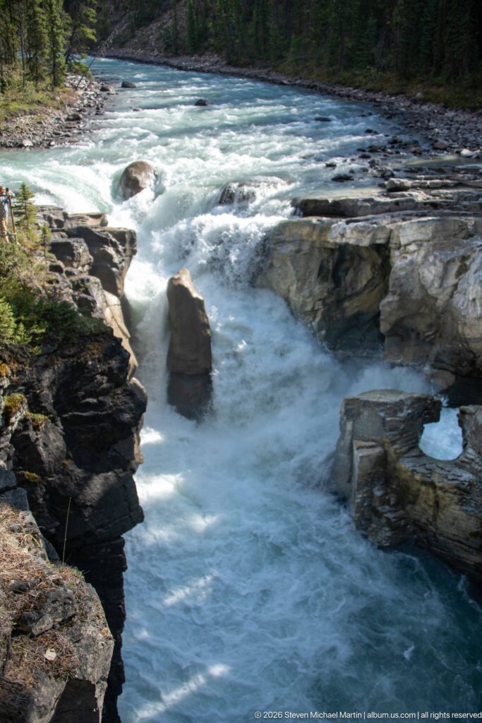 White water funnels around a tall central rock as the Sunwapta River enters the narrow gorge.