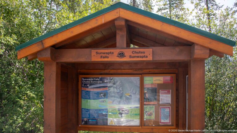 Wooden gabled Parks Canada kiosk displaying bilingual Sunwapta Falls maps and visitor information.