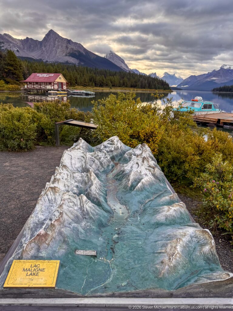 A painted three-dimensional relief model labeled Maligne Lake fills the foreground, with visitor buildings, docks, lake, and mountains behind