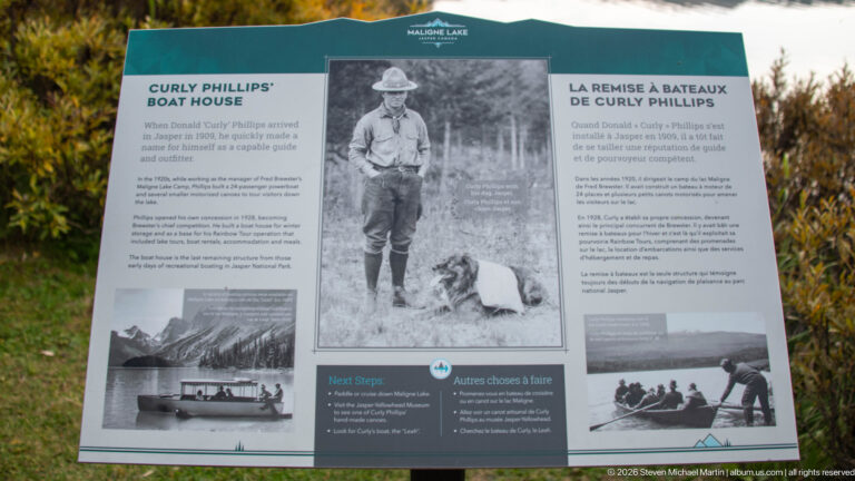 Bilingual Maligne Lake interpretive panel with historic photographs about Curly Phillips and early boats on the lake.