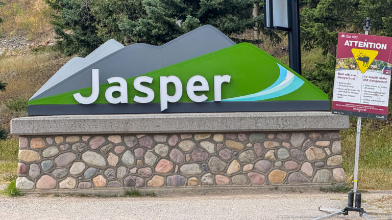Jasper monument appears beside a temporary bilingual Attention wildlife warning sign with an elk graphic