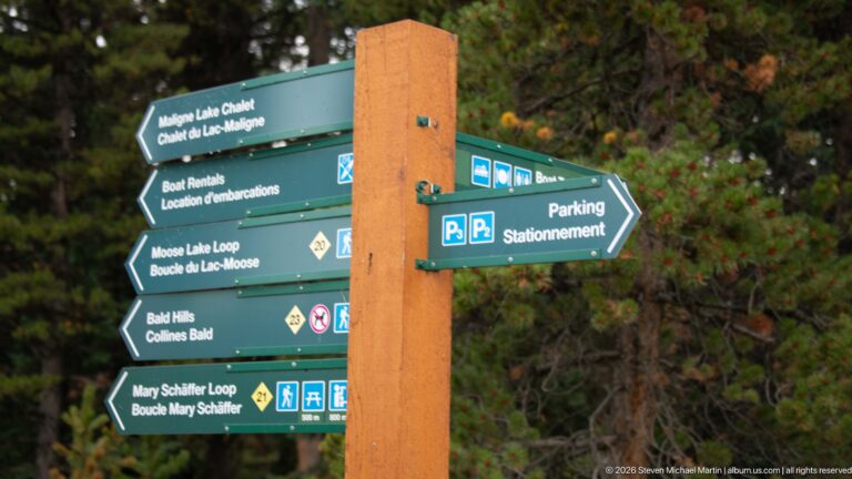 A multi-arm signpost directs visitors to Maligne Lake Chalet, boat rentals, parking, Moose Lake Loop, Bald Hills, and Mary Schäffer Loop