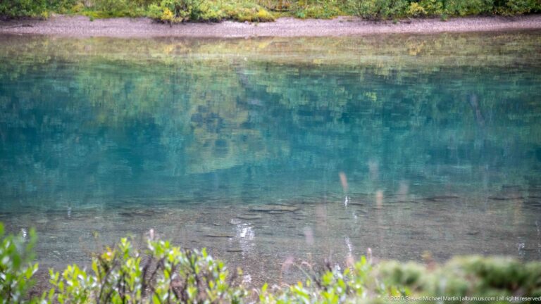 Transparent turquoise water reveals the lake bottom and submerged stones near shore