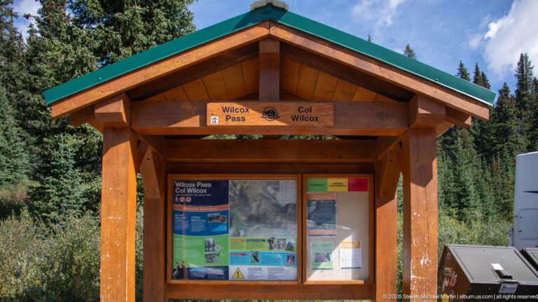 Wooden trailhead kiosk labeled Wilcox Pass and Col Wilcox with maps and visitor information panels.