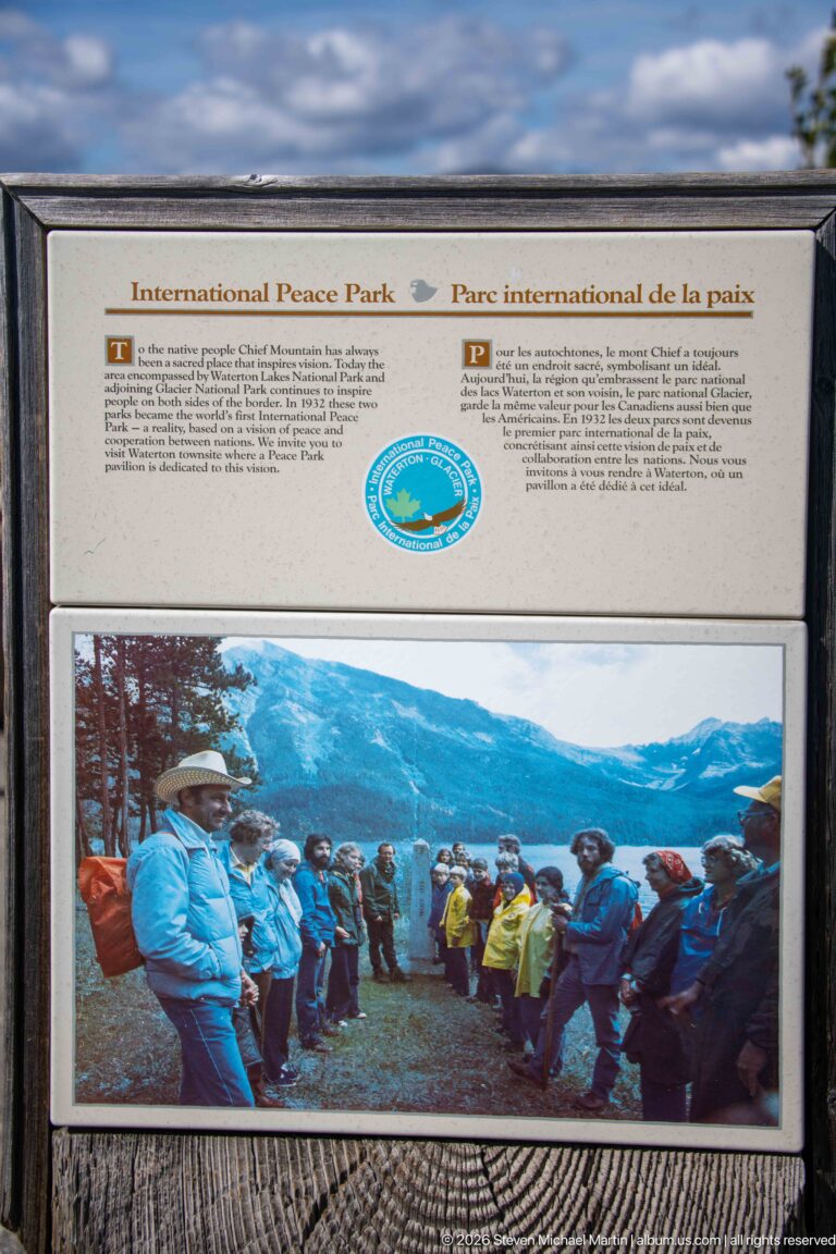 Bilingual International Peace Park panel with circular emblem and archival photograph of a group gathered at a mountain viewpoint.