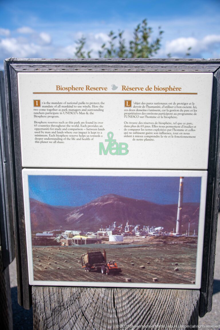 Bilingual Biosphere Reserve interpretive panel with explanatory text and a historic photograph of buildings and a tall industrial structure.