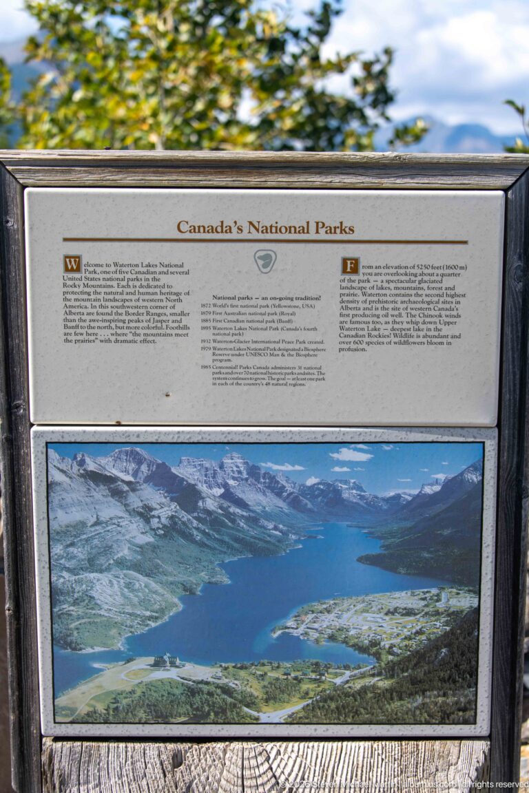 Outdoor interpretive panel titled Canada’s National Parks with bilingual text and a panoramic mountain-lake photograph.