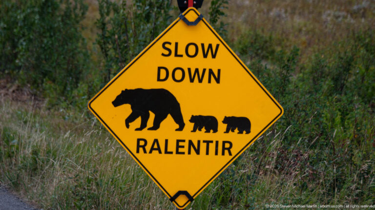 Yellow diamond sign reading Slow Down and Ralentir with silhouettes of an adult bear and two cubs.
