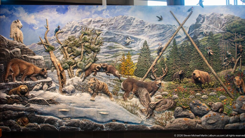 Detailed mountain ecosystem mural filled with bears, ungulates, birds, small mammals, forest, stream, and alpine peaks.