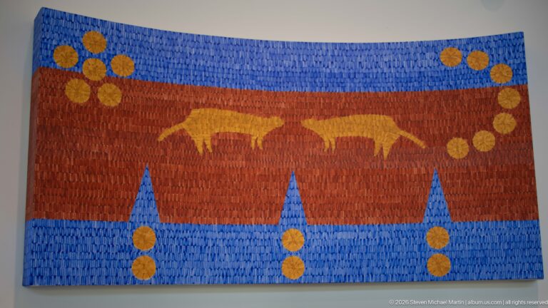 Large blue and rust textile wall hanging with two golden bison silhouettes and repeating circular motifs.