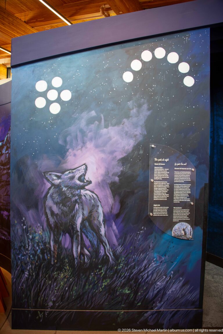 Large dark blue-purple mountain exhibit with arc of white moon-like circles, bilingual text, and small display object.