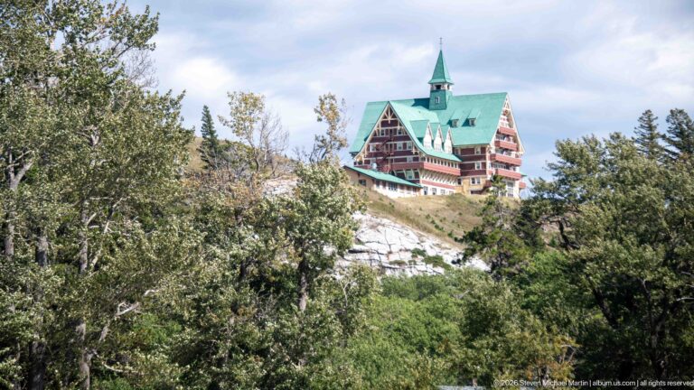 Prince of Wales Hotel with green roof and central tower seen above leafy trees on a hillside.