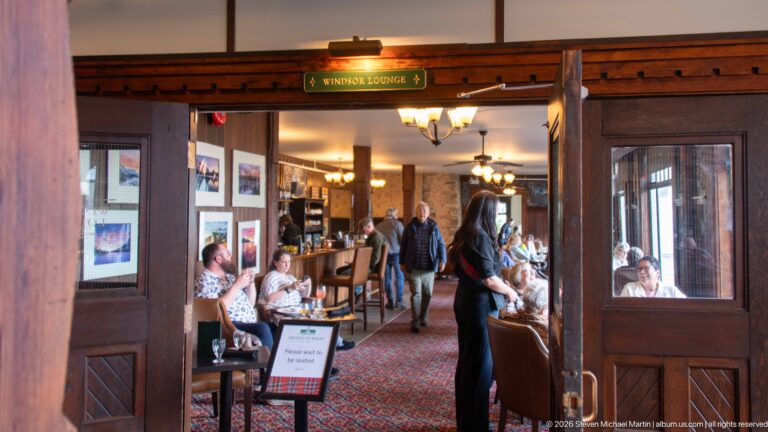 Open wooden doors marked Windsor Lounge lead into a busy dining room with seated guests and a server.
