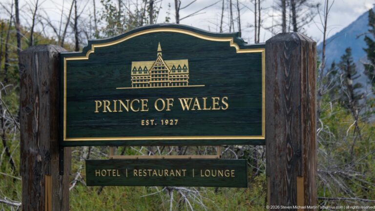 Close view of dark green Prince of Wales sign with gold hotel silhouette, “Est. 1927,” and service panel below.