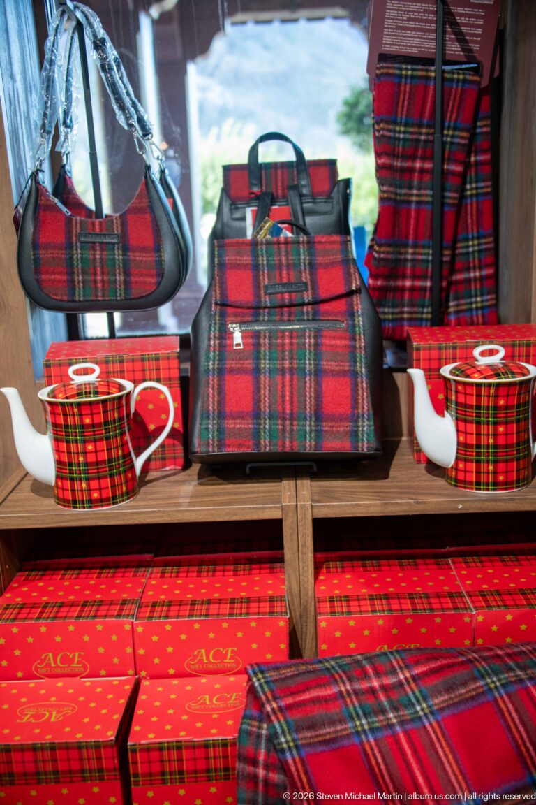 Red tartan bags, boxes, and ceramic teapots arranged together on a hotel shop display.