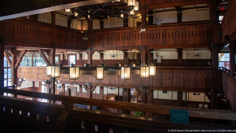Upper-level view across stacked timber balconies and hanging lanterns in the Prince of Wales Hotel lobby.
